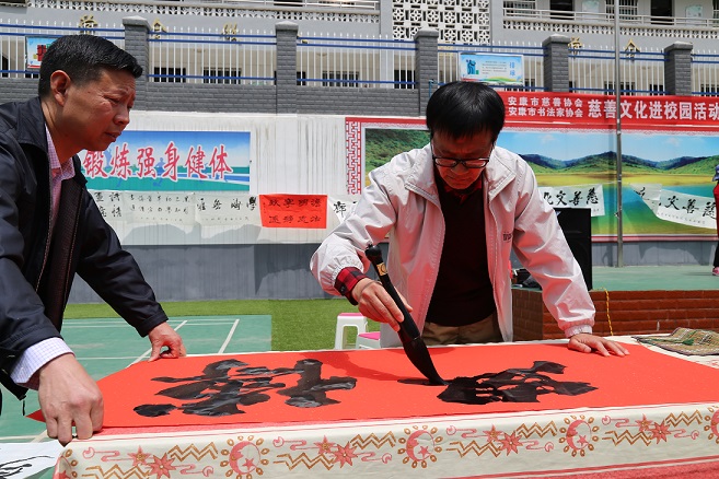 图为市慈善协会联络安康书画家马昌琪为大道九年制学校书写慈善书画.